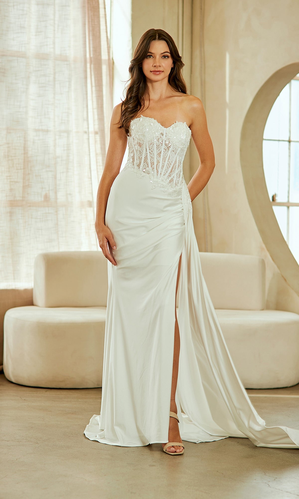 Woman wearing a white strapless gown with a slit in a room with beige decor